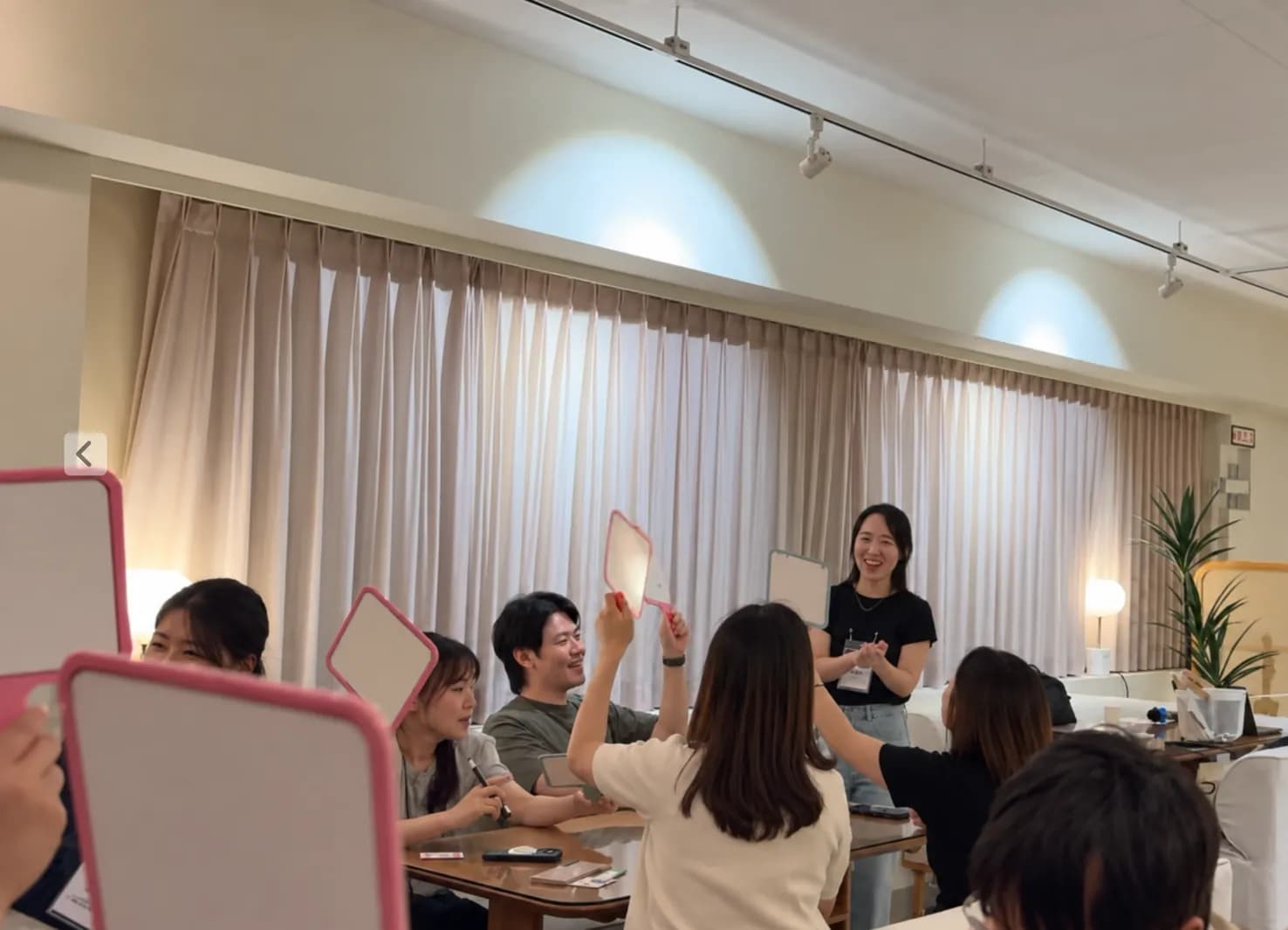 Y-BAR 365 라이브에서 참여자가 마이크로 이야기하고 동료들이 보드를 들어 반응하는 장면